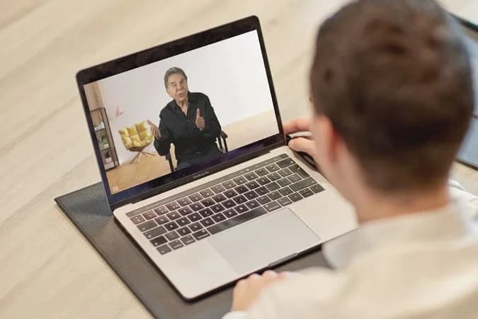 A learner watching Dr. Robert Cialdini teach a Certified Practitioner video lesson on a laptop