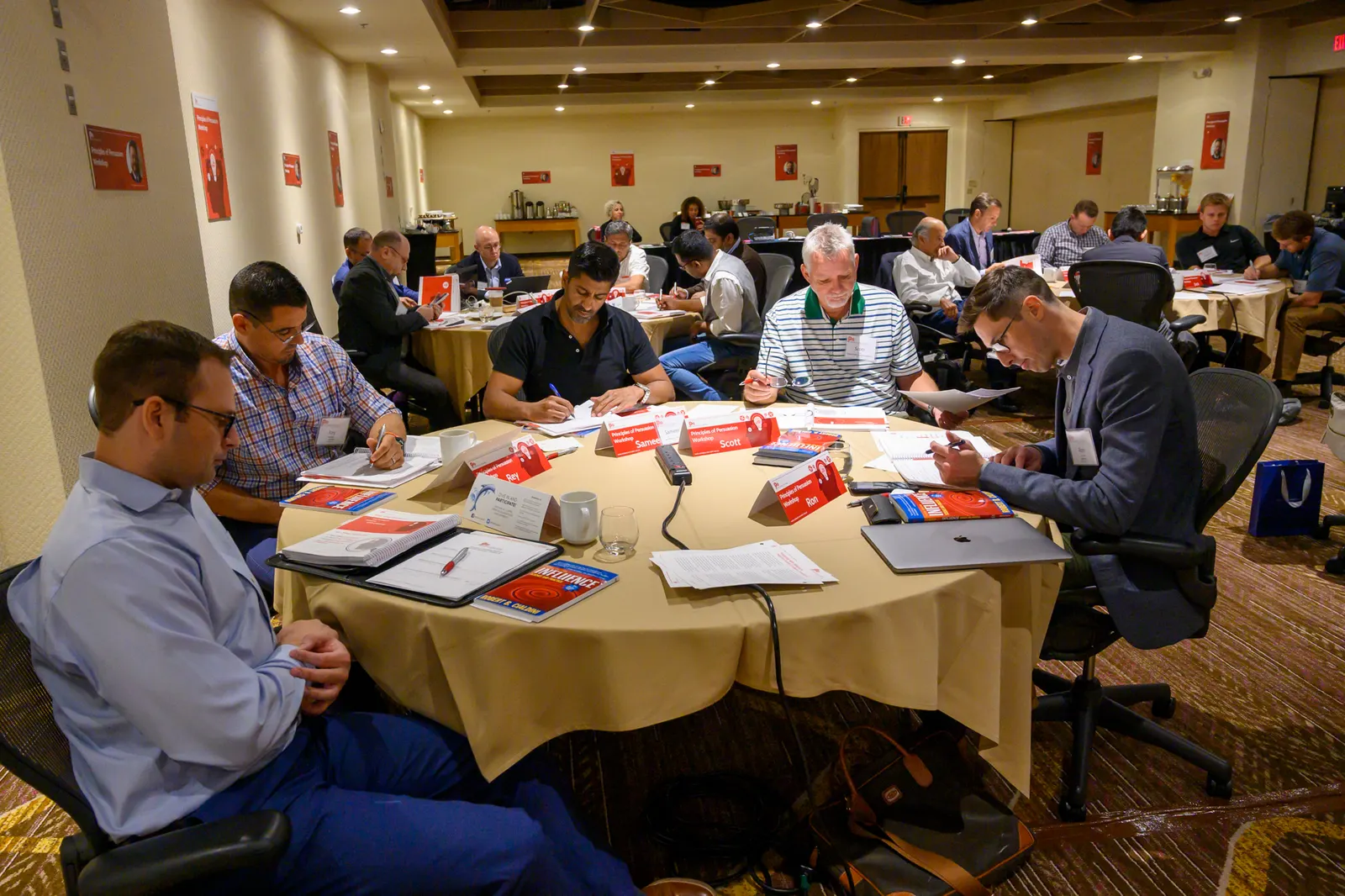 A full room of participants at round tables during a Principles of Persuasion workshop