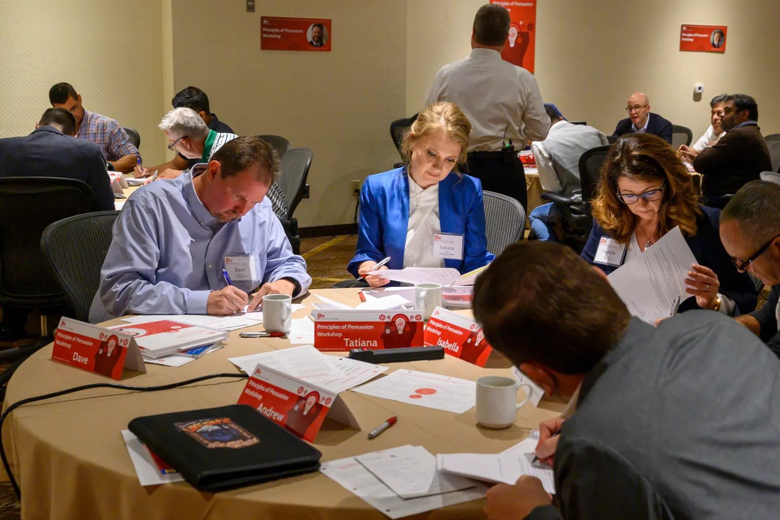 Workshop participants writing on their worksheets at a shared table